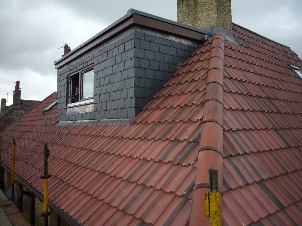 Roofer repairing damaged roof tiles